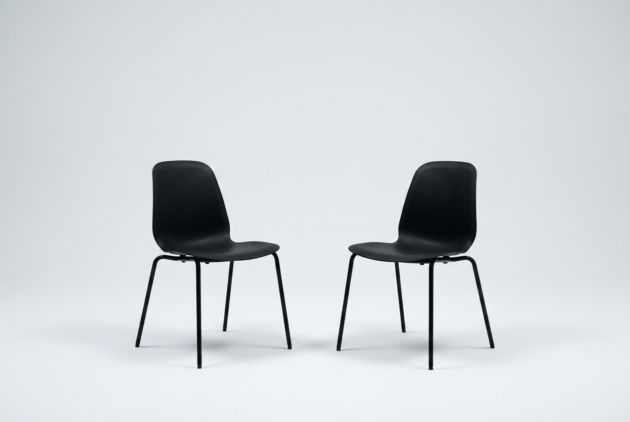 Two empty chairs turned toward each other in a white studio, set for a one-on-one conversation